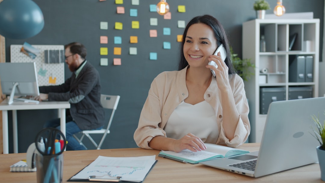 Woman talking on phone at desk with laptop